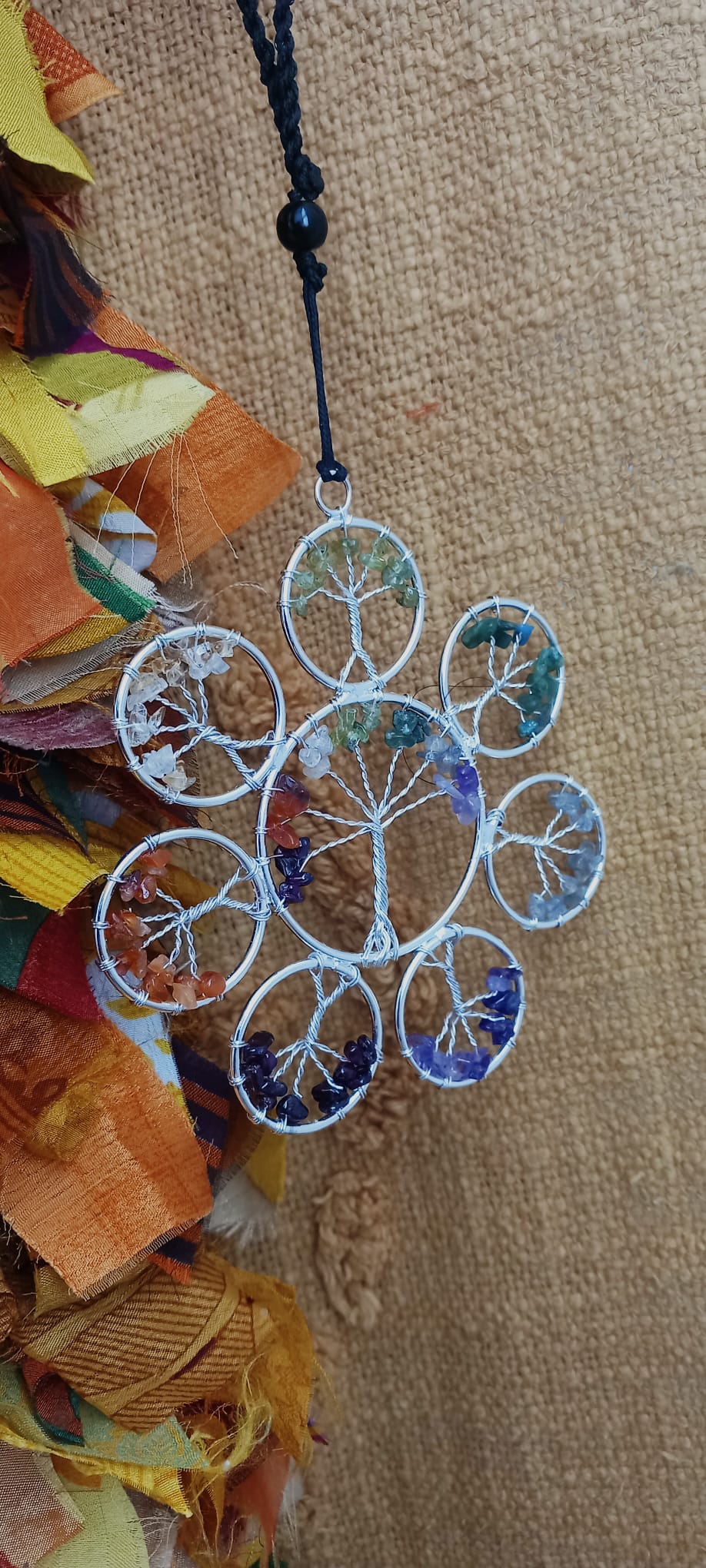 Una pieza armoniosa para el alma y los sentidos. Este colgador móvil de viento combina minerales y metal en un diseño artesanal con gran carga estética y natural. Su flor de loto central tallada con árbol y minerales sostiene varios tubos de cobre y minerales decorativos con piedras naturales sin pulir reales colgantes que, al moverse con la brisa, producen un ambiente suave y relajante. Una pieza ideal para llenar de calma y energía positiva cualquier espacio, tanto interior como exterior.