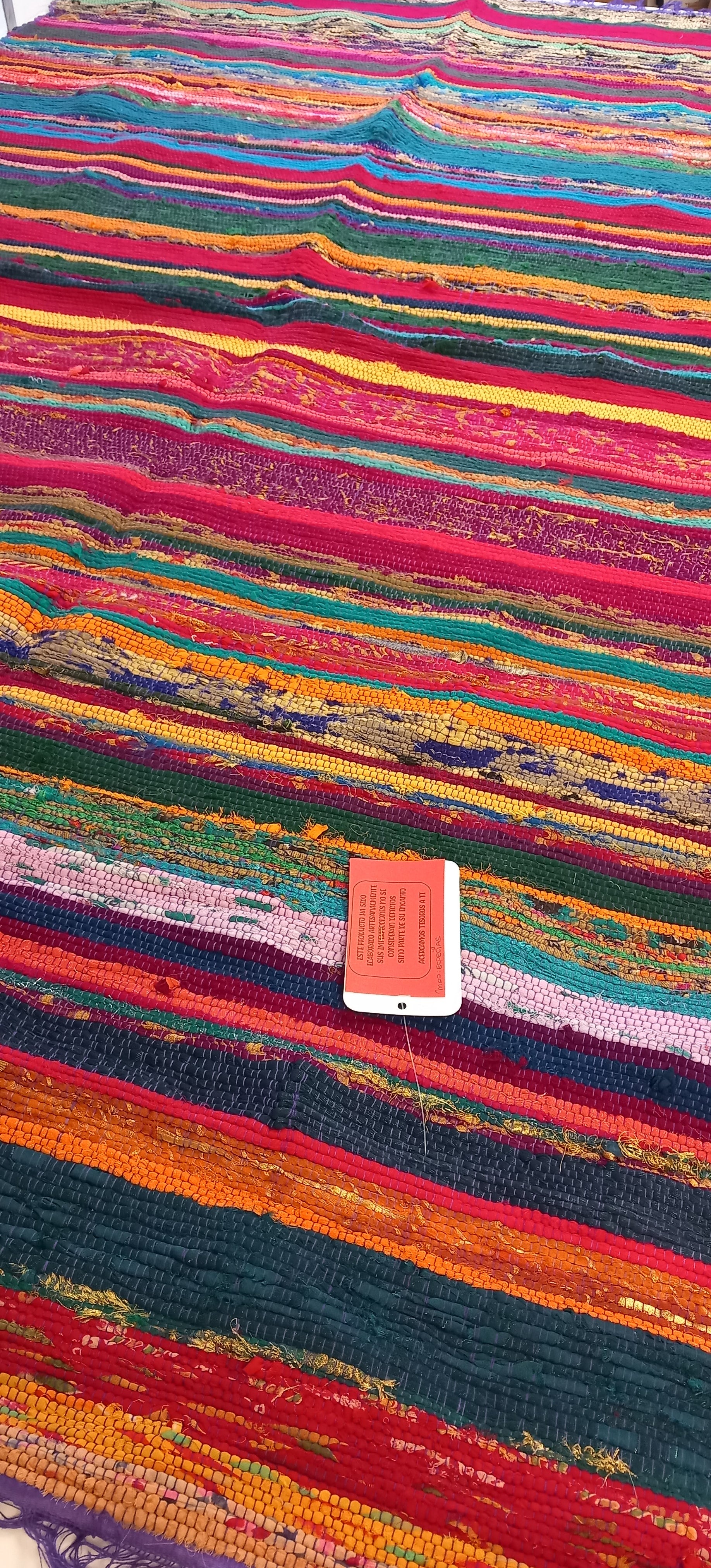 Una explosión de color, textura y tradición en una sola pieza. La jarapa multicolor de 100x200 cm está elaborada artesanalmente con retales de algodón tratados con tintes naturales, lo que da como resultado una alfombra única, vibrante y cargada de carácter. Su diseño mezcla tonos de forma armónica, creando un efecto visual atractivo y cálido. Además de usarse como alfombra, es perfecto como tapiz de pared, cubrecama o para renovar el estilo de muebles y sofás.