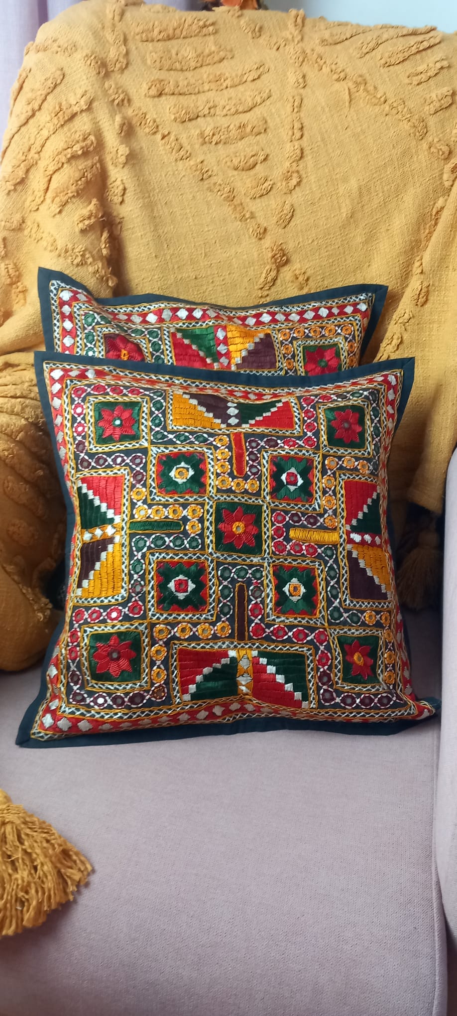Un toque bohemio y artesanal para cualquier espacio. Esta funda de cojín Old Banjara es una pieza única, confeccionada con retales de tejidos tradicionales llenos de historia. Sus vibrantes bordados, detalles en espejos y abalorios la convierten en un complemento perfecto para quienes buscan decorar con personalidad y autenticidad. Su apertura trasera facilita la colocación del relleno, aportando comodidad y practicidad.