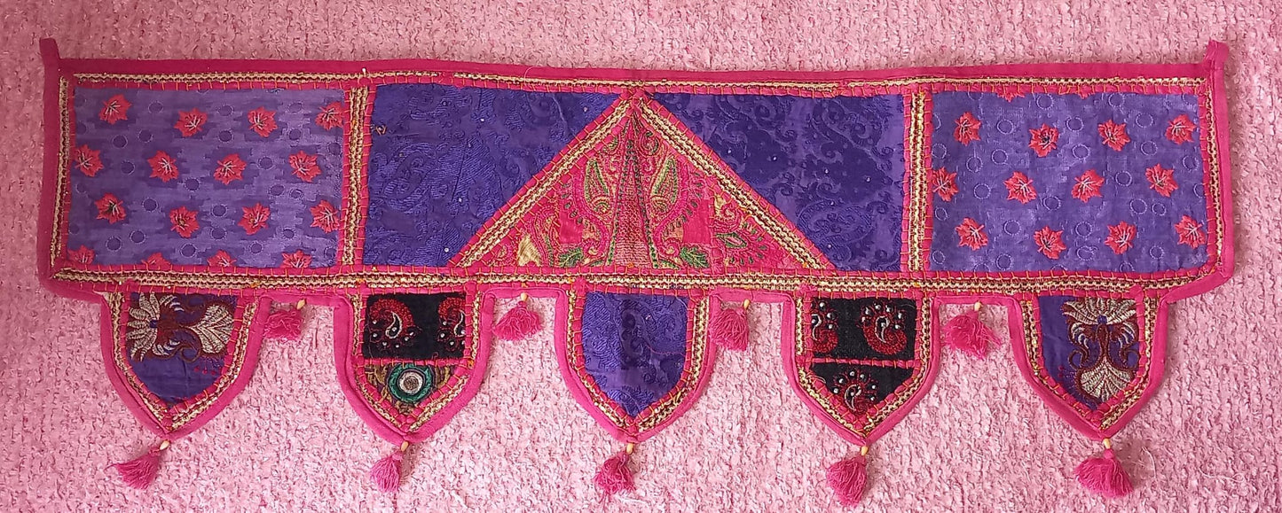 Un toque de tradición y elegancia en cada espacio. El Toran Bordado Patchwork es una pieza artesanal única, confeccionada en algodón con diferentes telas bordadas e hilos metálicos dorados que le aportan un brillo sutil y cómodo. Utilizado en la decoración tradicional hindú para embellecer puertas y atraer buenas energías, su versatilidad permite que también sea perfecto para decorar paredes, muebles, escaparates, mostradores o stands de mercado.