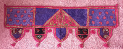 Un toque de tradición y elegancia en cada espacio. El Toran Bordado Patchwork es una pieza artesanal única, confeccionada en algodón con diferentes telas bordadas e hilos metálicos dorados que le aportan un brillo sutil y cómodo. Utilizado en la decoración tradicional hindú para embellecer puertas y atraer buenas energías, su versatilidad permite que también sea perfecto para decorar paredes, muebles, escaparates, mostradores o stands de mercado.