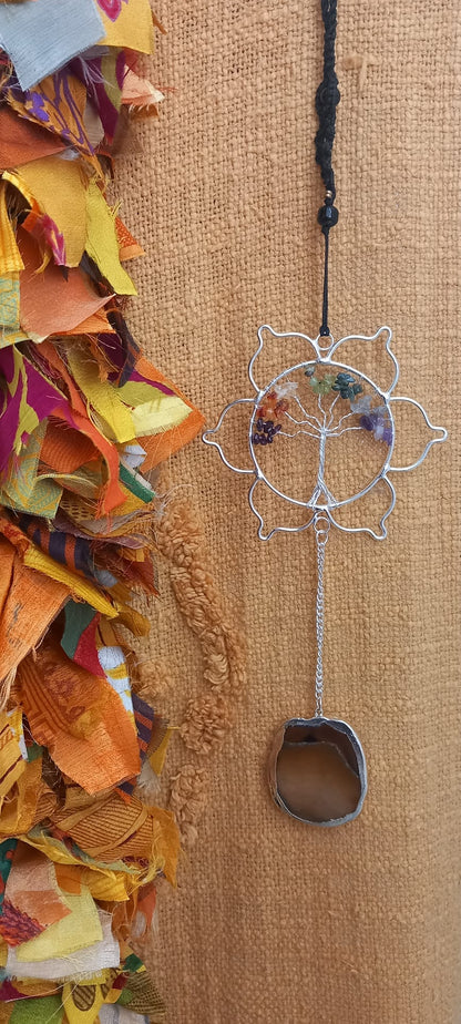 Una pieza armoniosa para el alma y los sentidos. Este colgador móvil de viento combina minerales y metal en un diseño artesanal con gran carga estética y natural. Su flor de loto central tallada con árbol y minerales sostiene varios tubos de cobre y minerales decorativos con piedras naturales sin pulir reales colgantes y el ágata colgante que, al moverse con la brisa, produce un ambiente suave y relajante. Una pieza ideal para llenar de calma y energía positiva cualquier espacio, tanto interior como exterio