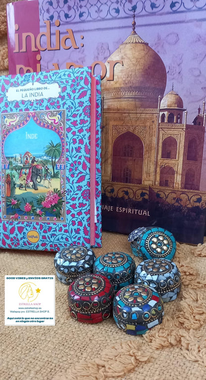 Un pack de 6 unidades, lleno de pequeños tesoros artesanales. Este conjunto de 6 mini cajas metálicas redondeadas de la colección Navarantha destaca por su exquisita decoración estilo mosaico, elaborada con diferentes piezas de mineral. Cada cajita mide aproximadamente 4 cm y es una pieza única, ideal como detalle decorativo, joyerito o regalo simbólico. Perfectas para llenar tu tienda de color, brillo y magia artesanal, son el tipo de producto que cautiva por su originalidad y delicadeza.