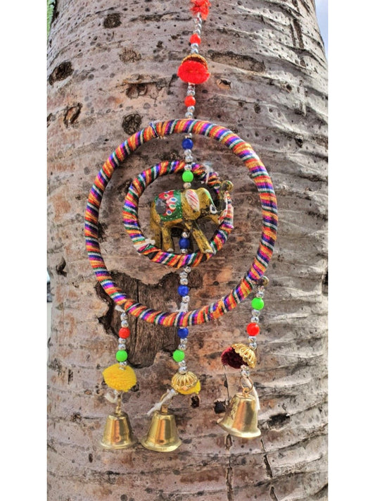 Un colgador encantador que combina tradición y ternura. Este móvil decorativo está elaborado artesanalmente con tela y presenta una estructura circular de la que cuelgan campanas metálicas que producen un suave sonido al moverse con el aire. En su centro, un elefante de la suerte aporta un toque simbólico y alegre. Perfecto para decorar habitaciones infantiles, escaparates o como detalle especial en un rincón de tu hogar. Su estilo suave y colorido lo convierte en un regalo ideal.